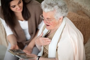 young woman and elderly woman looking a photo or memory book